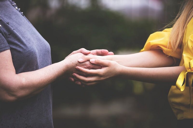 Two women holding hands in support