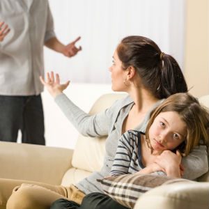 mother holding daughter and waving off father