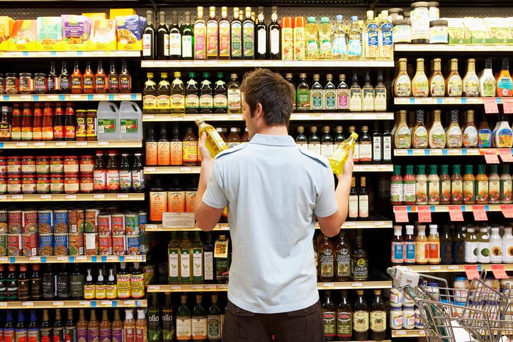 Comparing bottles in grocery store aisle