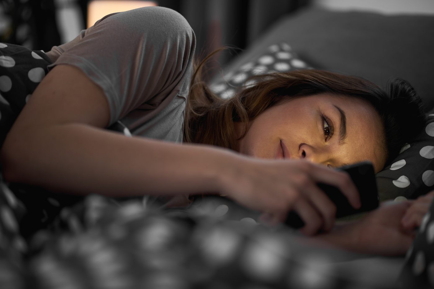 Girl using smart phone and lying down in bed