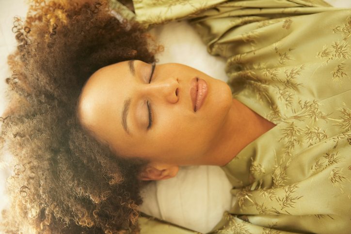 person in green silk robe with eyes closed