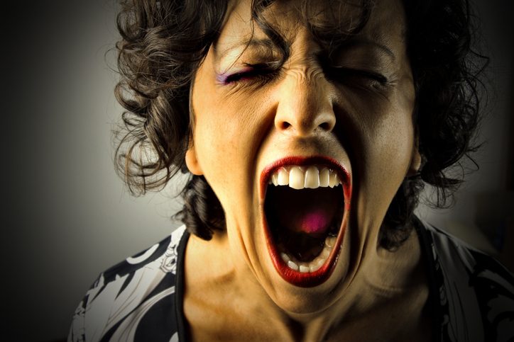 Person's face with eyes closed, mouth open in a scream