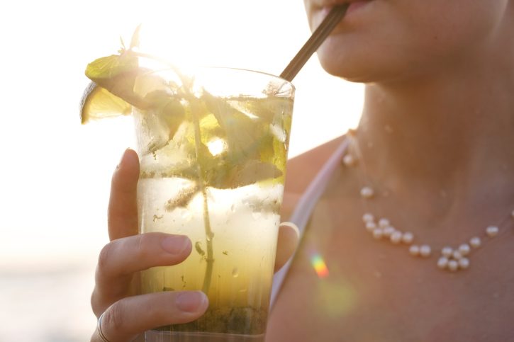 A female sips on an alcoholic beverage outside