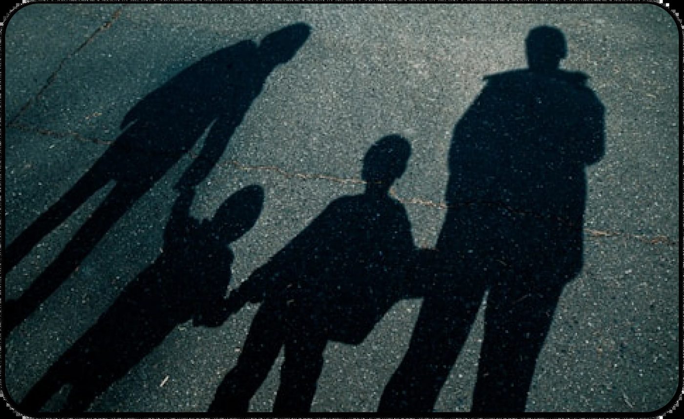 Cropped shadow of a family on asphalt, symbolizing the unseen presence of intergenerational trauma.