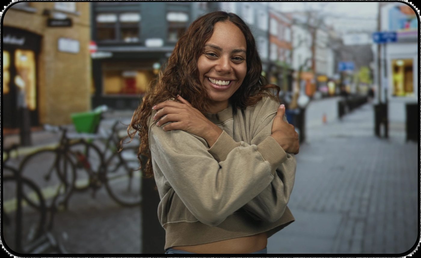 woman smiling and embracing herself to show self-kindness and emotional well-being