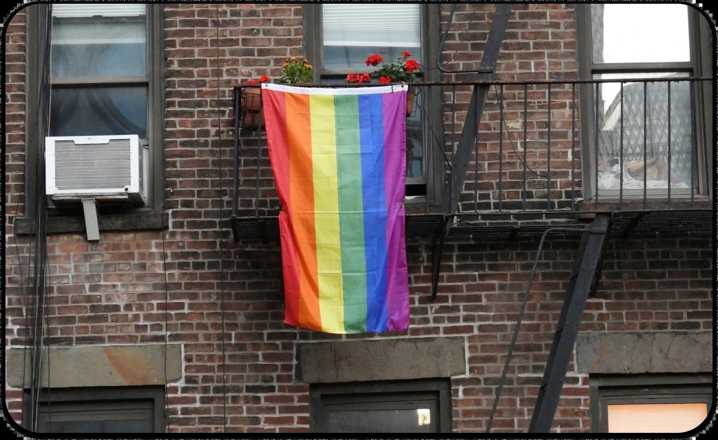 Attachment-Focused EMDR shown through a rainbow pride flag on a city apartment window.
