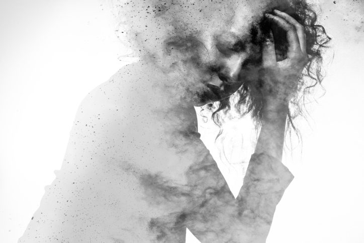 faded grayscale photo of person with hand on head looking down