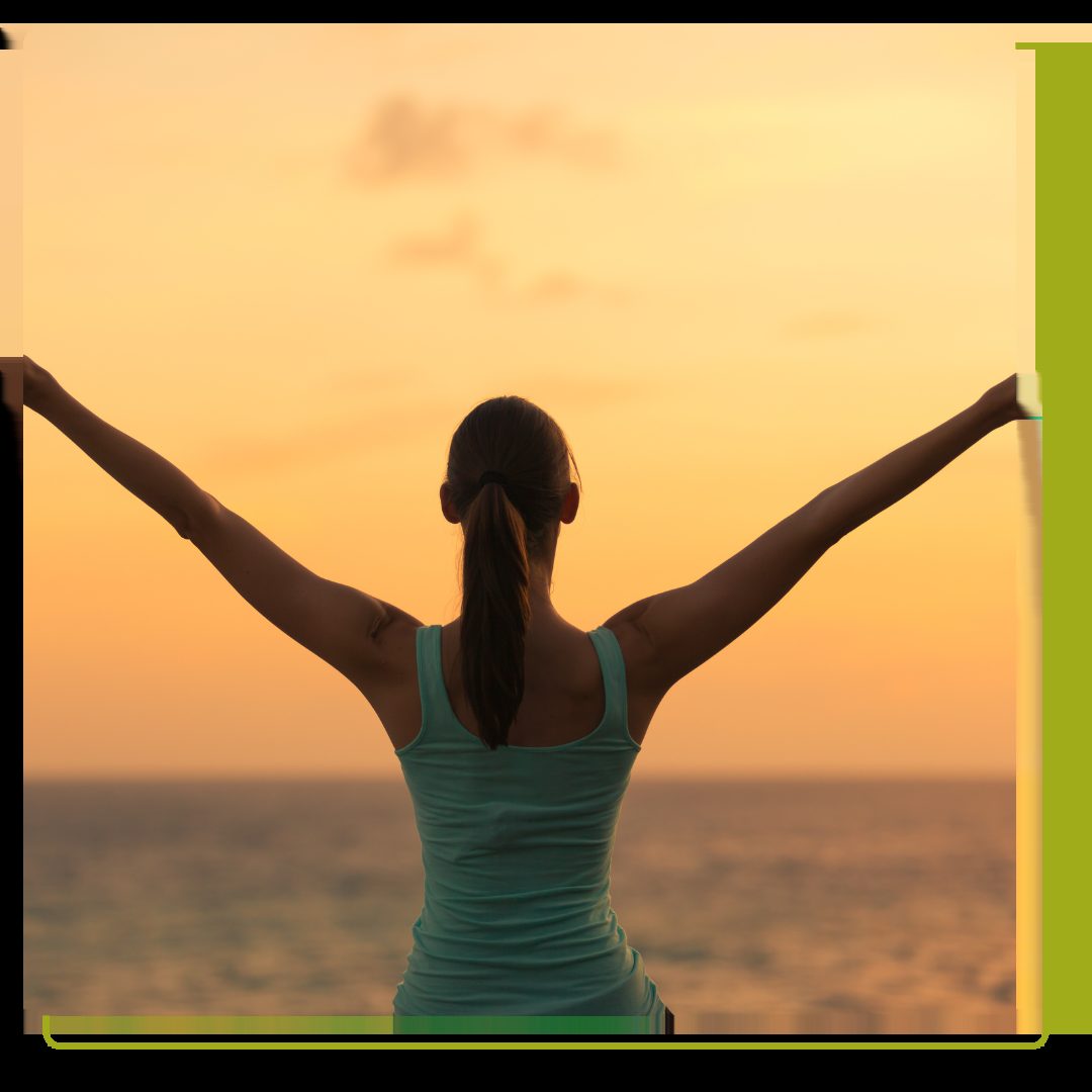 woman with hands in the air with sunset in background