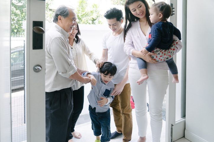Young family with children greet grandparents in doorway of house