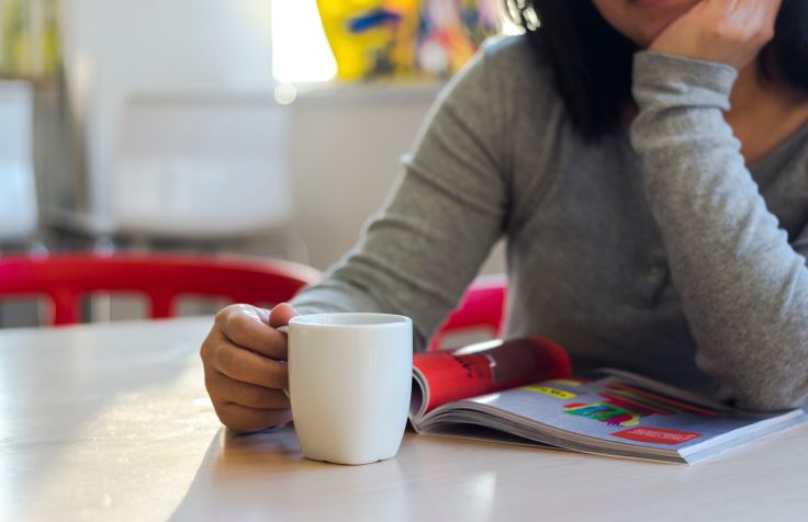 A woman looks at a magazine at her kitchen table
