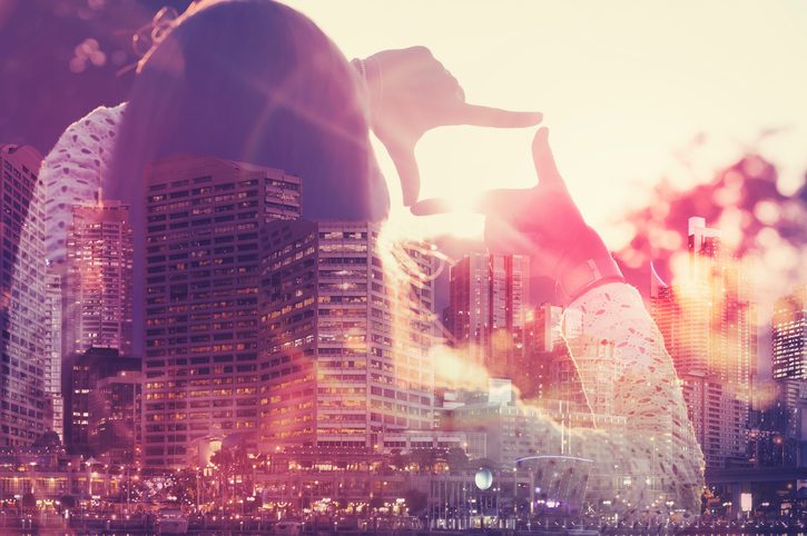 Double exposure of cityscape with person framing view in distance
