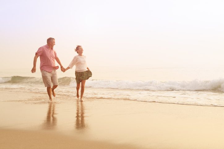 senior couple hand-in-hand outdoors on the beach