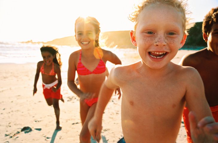 Group of children run along a beach