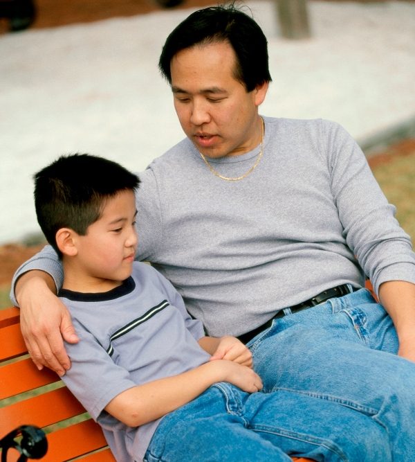 Father and son sitting on a park bench