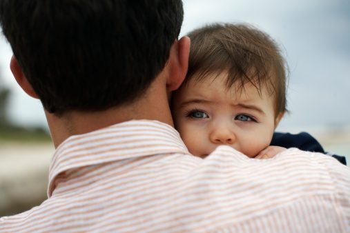 Father carrying baby daughter (15-18 months) outdoors, close-up