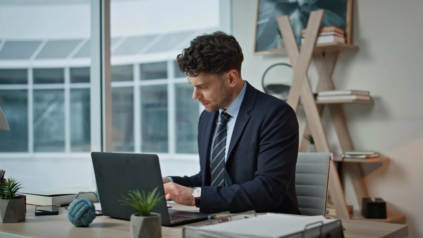 High-achieving professional working at a laptop and reflecting on success and fulfillment