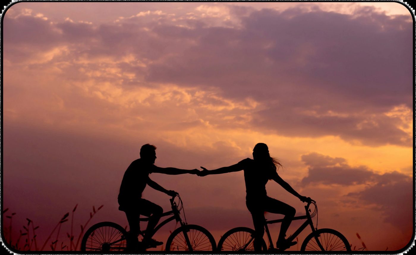 Silhouette of a couple on bicycles reaching out at sunset, symbolizing emotional distance and falling out of love