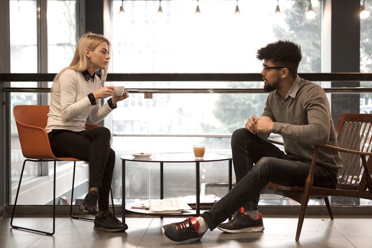 Two friends sitting separately having a serious conversation in cafe