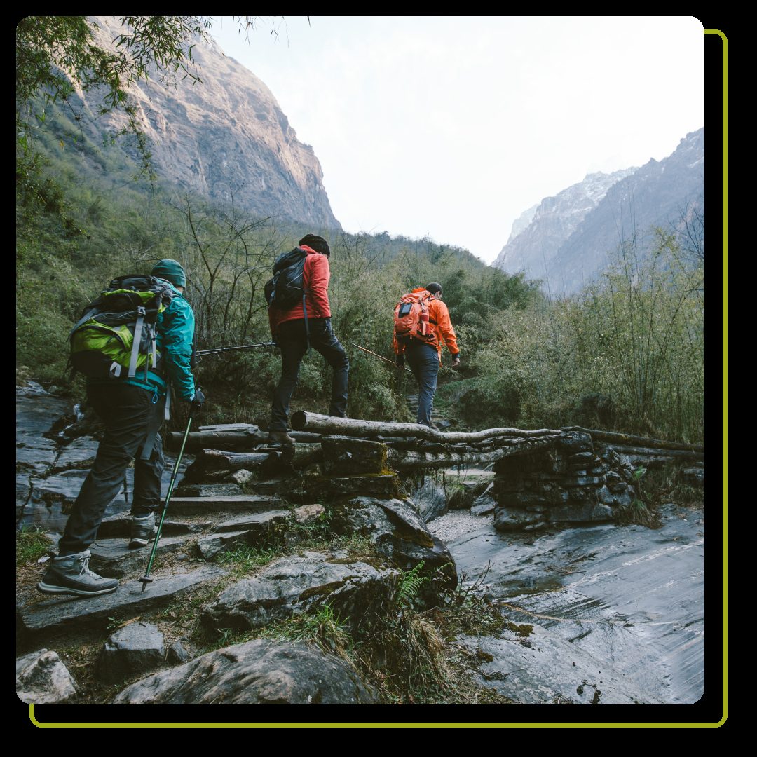 Three people walking across river on hike
