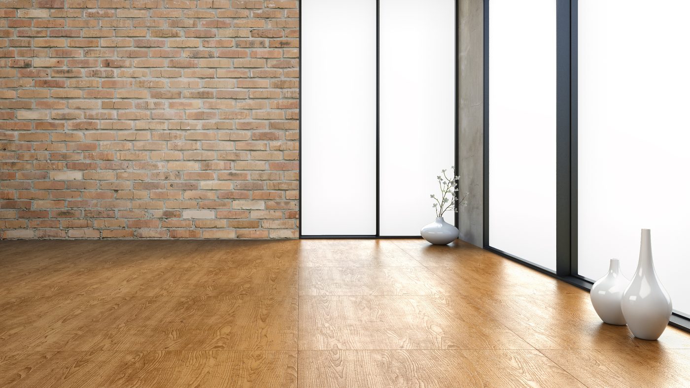 Empty office with wood floor, windows, brick walls, and vases.