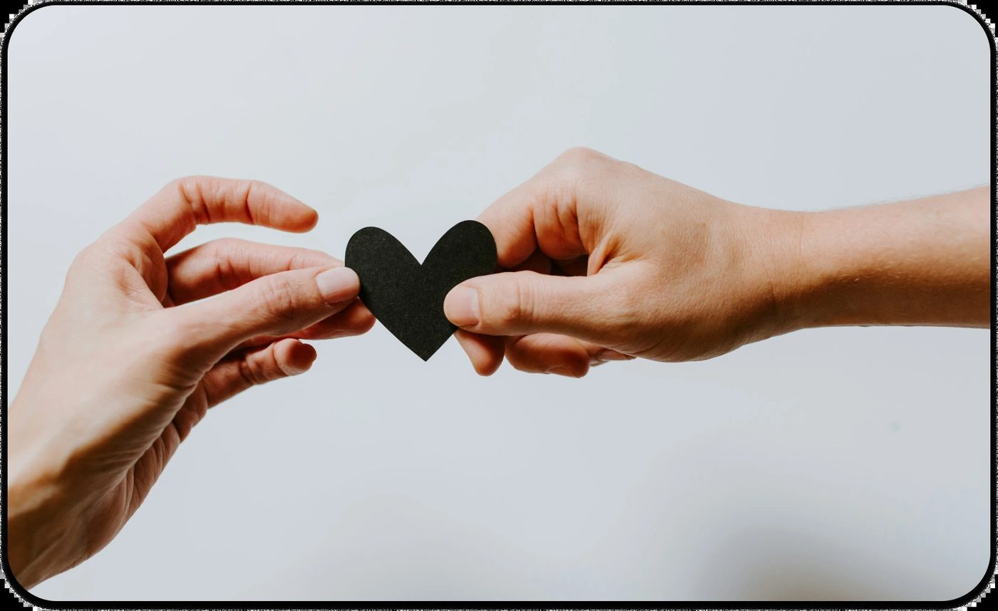 Hands exchanging a black heart symbolizing care, empathy, and suicide prevention