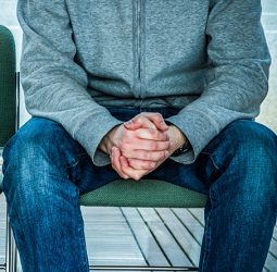 A waiting man with hands clasped