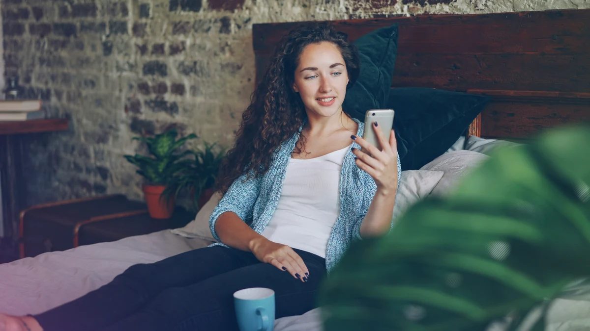 Person using a smartphone at home, representing cycle awareness and emotional self-care