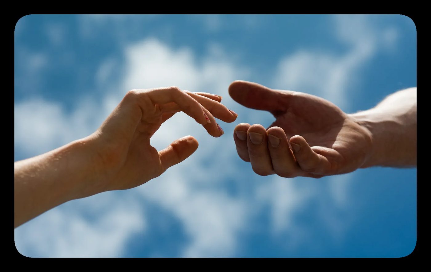 Two hands reaching towards each other against a blue sky, symbolizing human connection and the principles of interpersonal neurobiology.