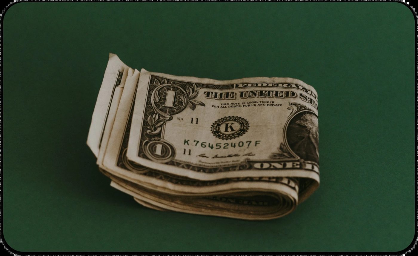 Close-up of stacked U.S. dollar bills on a green background representing money management and financial stress in financial therapy showing affordable therapy.