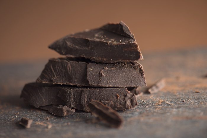 Pieces of dark chocolate with cocoa powder