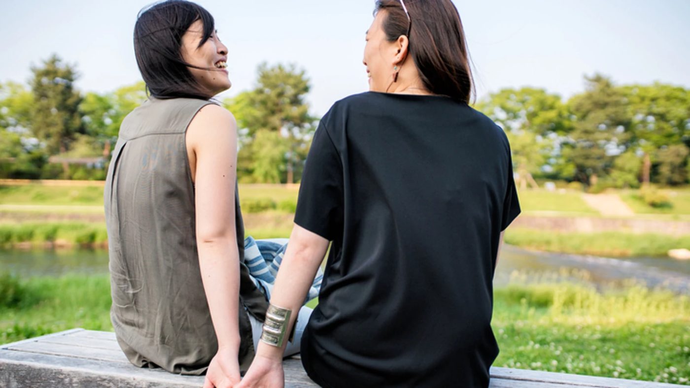Two people sitting together outdoors in a supportive conversation for an article about LGBTQ+ affirming therapy.
