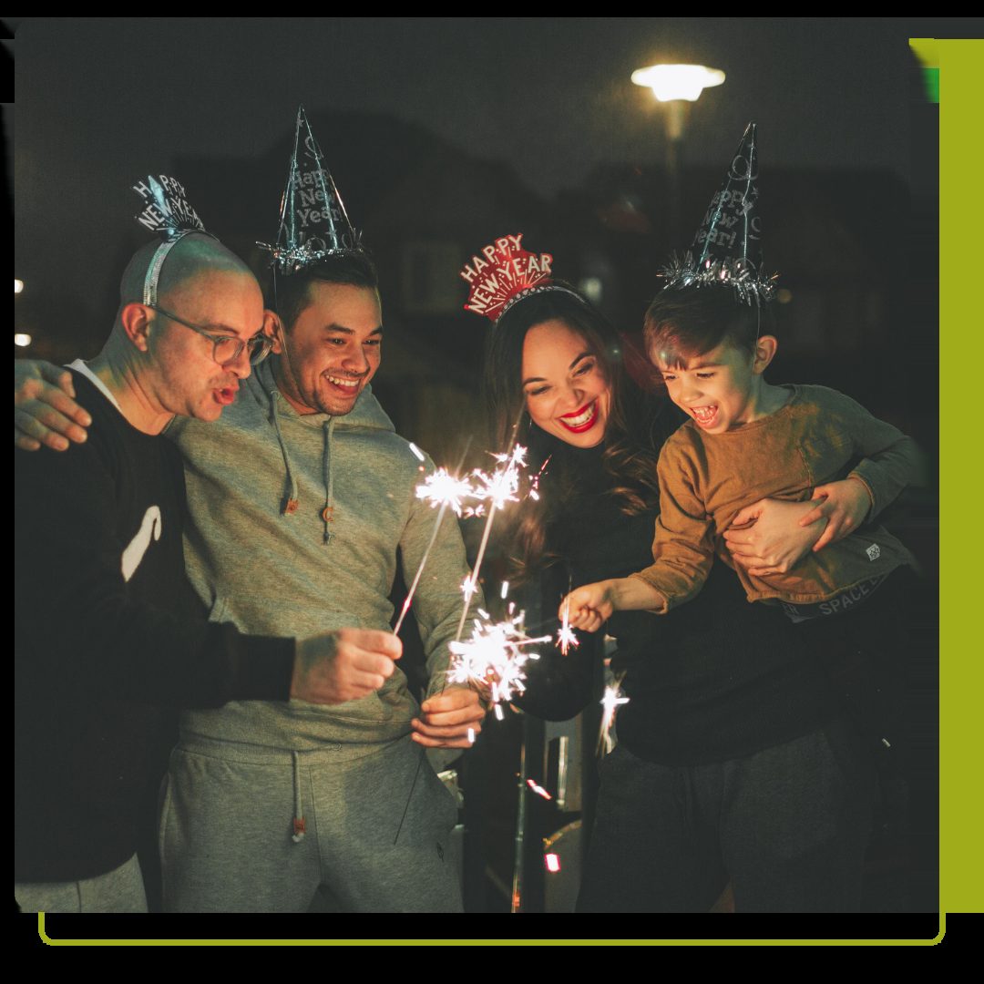 A family celebrating new years eve with party hats and sparklers.