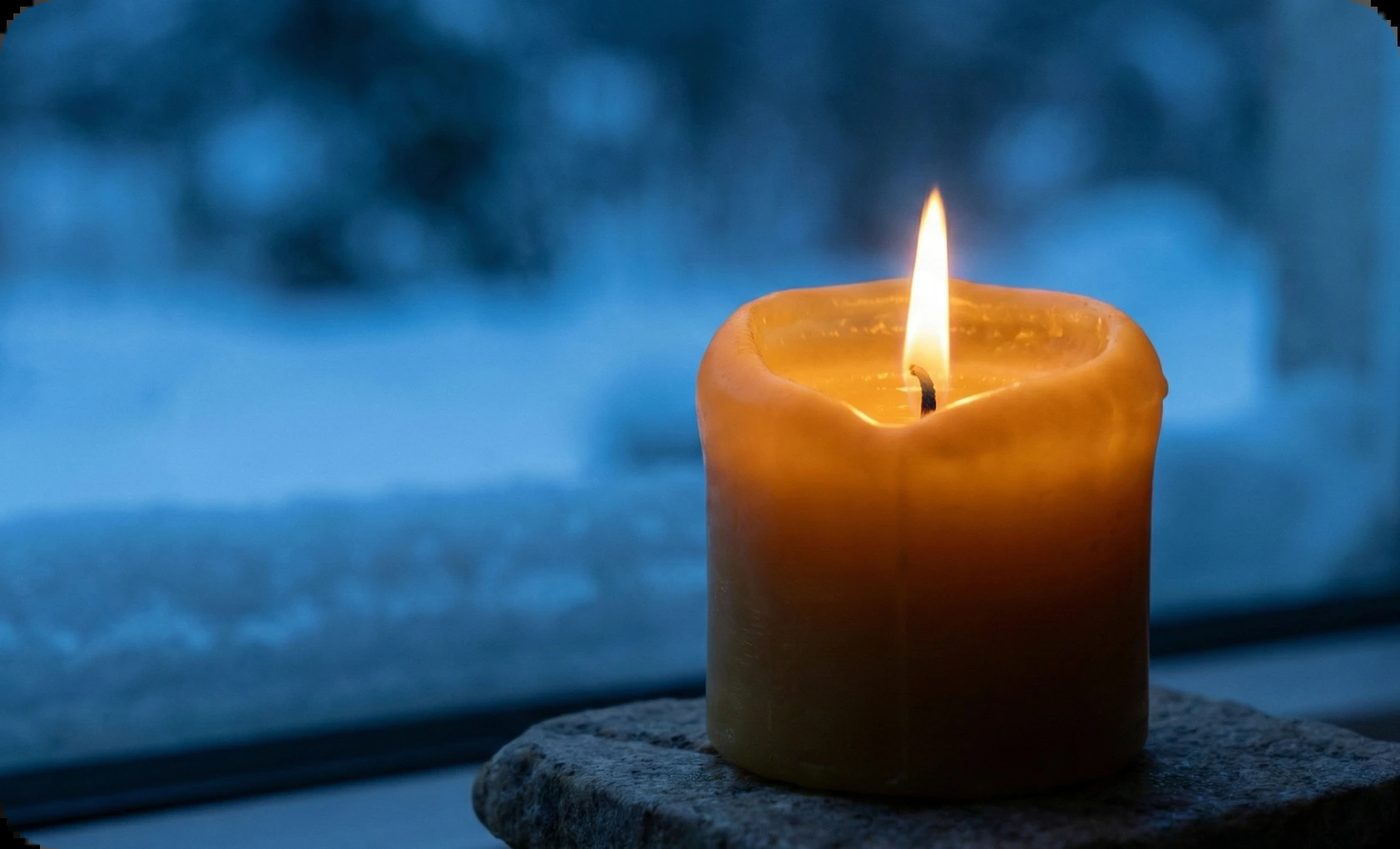 Warm glowing candle on a stone slab against a blurry blue winter window, symbolizing comfort against seasonal affective disorder.