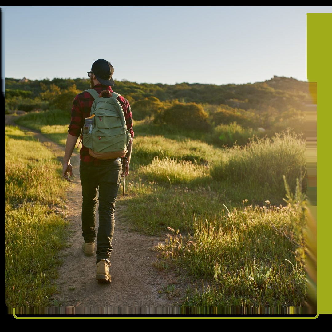 male hiker walking on a trail during sunset