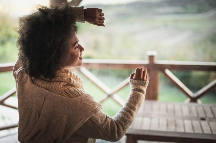 Woman leaning against window, happily looking outside