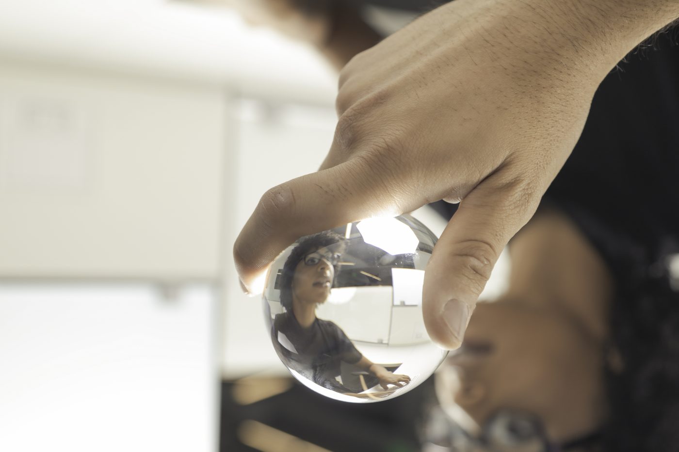 Person holds glass ball, in which they are reflected
