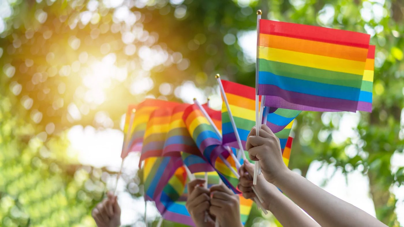 Pride flags raised in daylight for an article about LGBTQ+ affirming therapy and emotional safety.