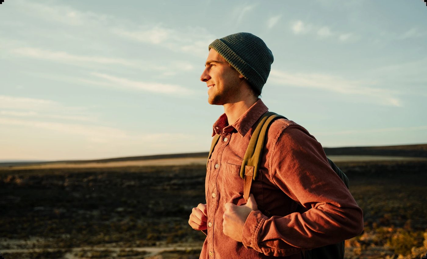 A young man with a backpack smiling outdoors, symbolizing finding closure and moving forward with hope
