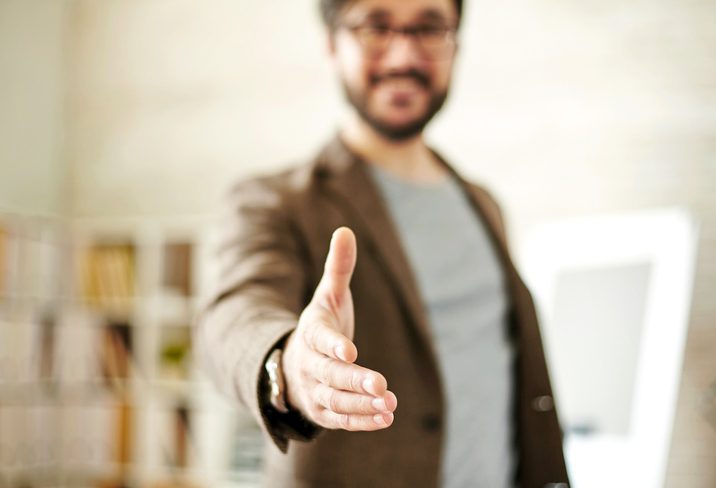 Unfocused photo of person holding out hand to shake