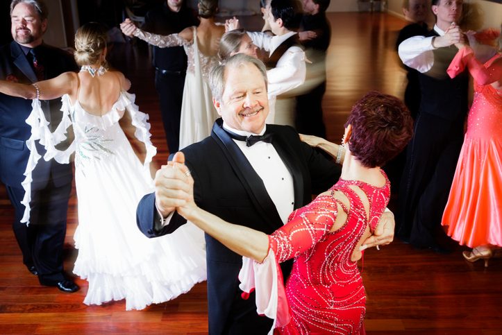 Overlooking view of several couples dancing in ballroom with hardwood floors