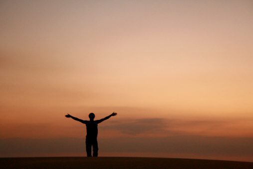 Silhouette of a man on a dune at sunset