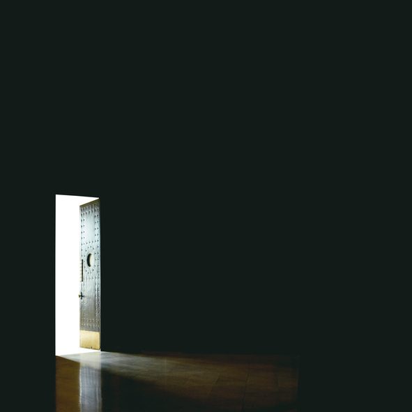 Door left open in dark room leads to bright sunlight outside