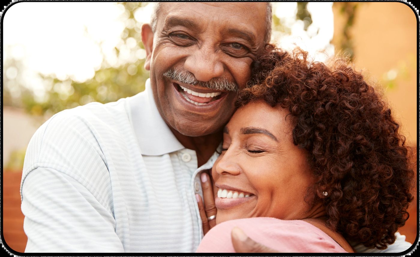 Smiling older man hugging a woman closely during Movember.