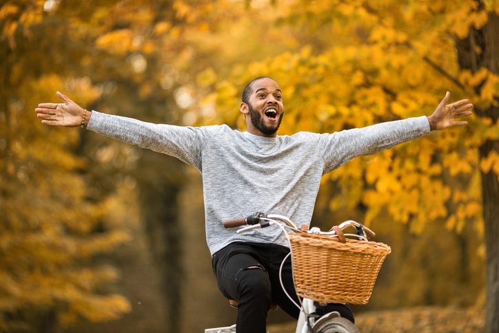 Happy person having fun while cycling with his arms outstretched in autumn day.