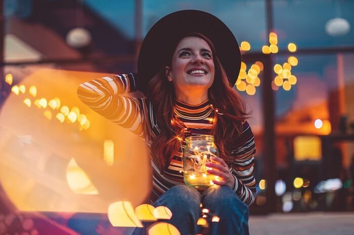 Smiling woman holding glowing string lights